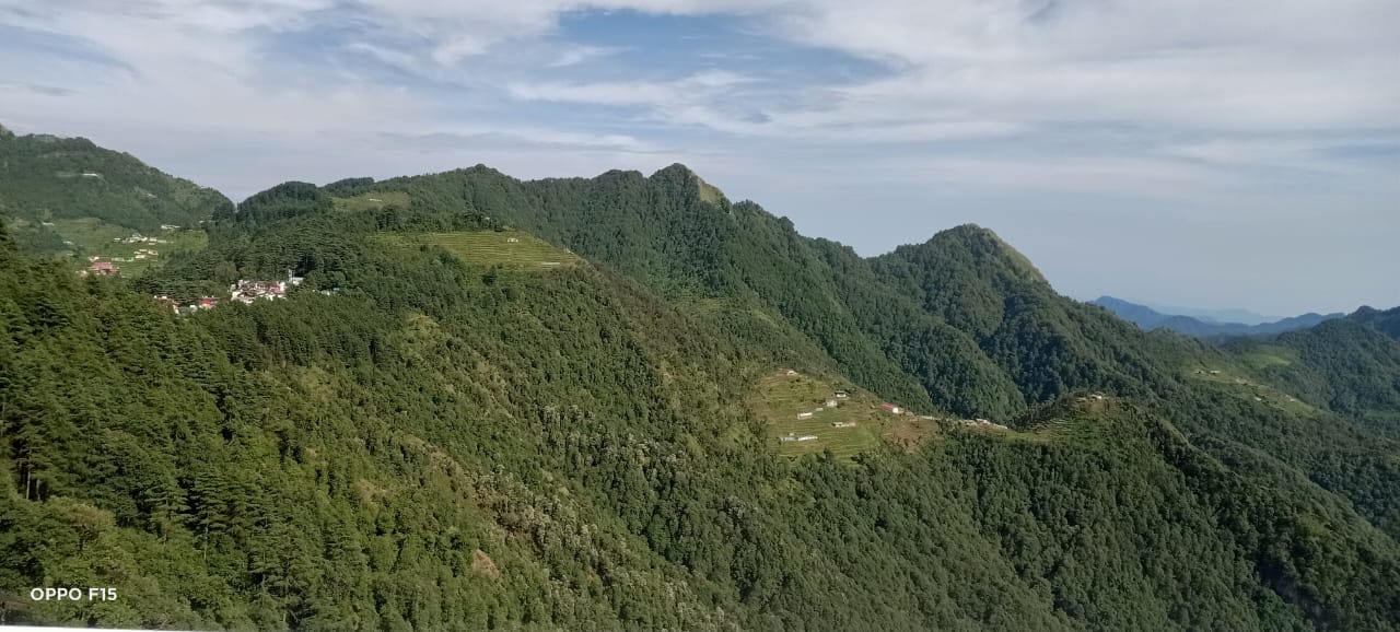 Sunlit green hills with small resorts in Dhanaulti